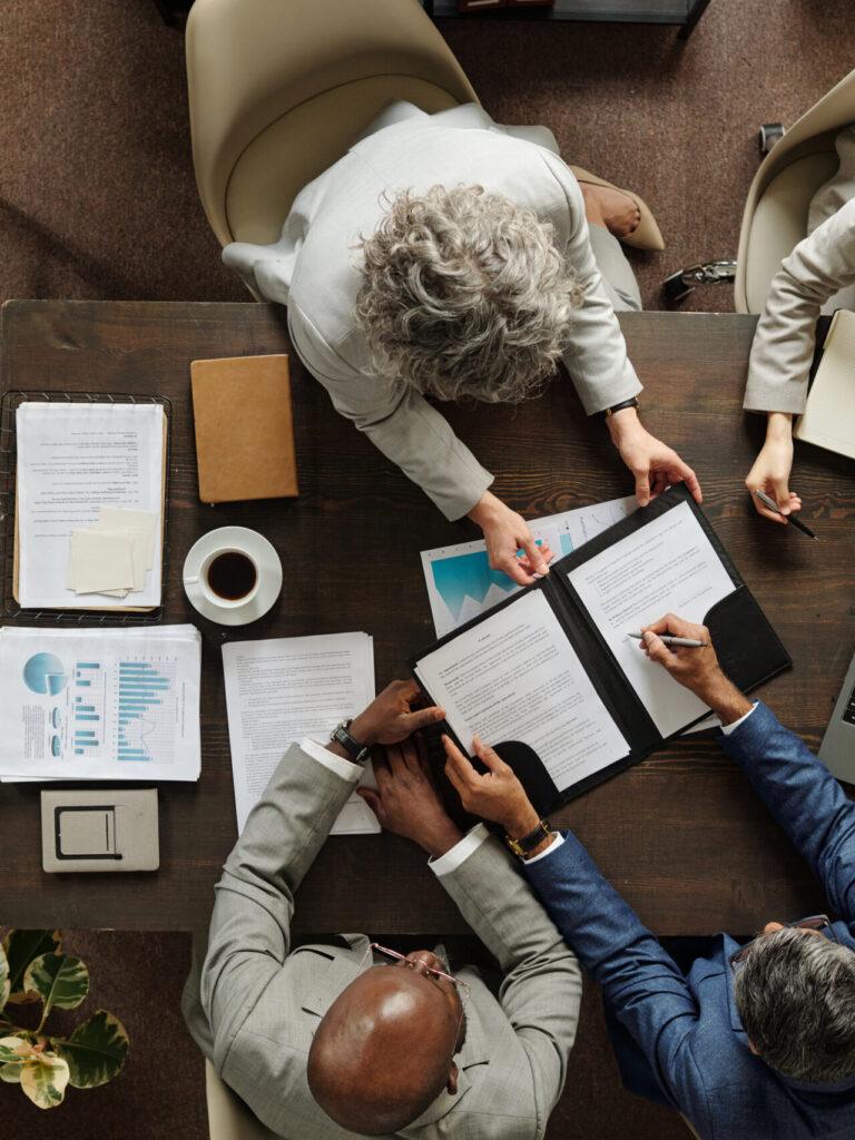 Professionals reviewing documents and data at table, supporting collaborative consulting, analytics insights, and strategic business decision-making