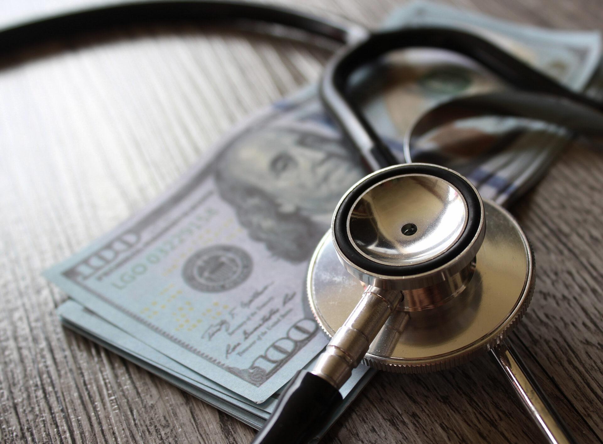 Stethoscope and money on wooden table. Healthcare, medical treatment cost and medicine concept.
